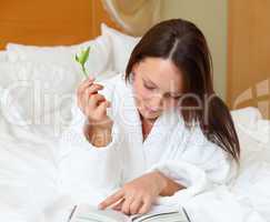 young woman in bed reading a book