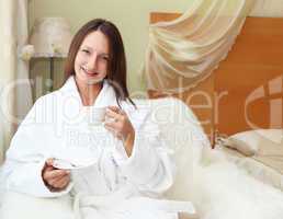 young woman in white robe drinking tea