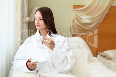 young woman in white robe drinking tea