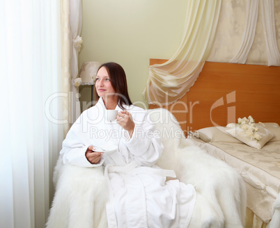 young woman in white robe drinking tea