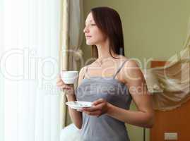 young woman drinking tea near the window