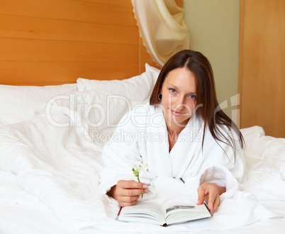 young woman in bed reading a book