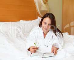 young woman in bed reading a book