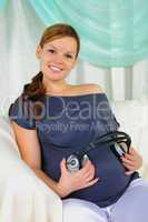 Pregnant woman holding headphones