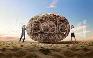 Businessman rolling a giant stone