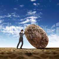 Businessman rolling a giant stone