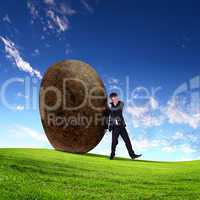 Businessman rolling a giant stone