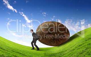 Businessman rolling a giant stone