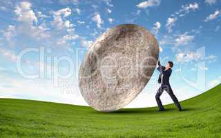 Businessman rolling a giant stone