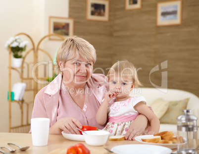 grandmother feeding granddaughter at home