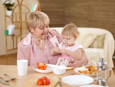 grandmother feeding granddaughter at home