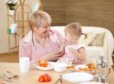 grandmother feeding granddaughter at home