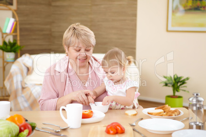 grandmother feeding granddaughter at home