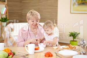 grandmother feeding granddaughter at home