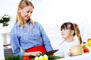 Young mother cooking at home with her daoghter
