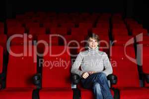 Young man sitting in the cinema alone