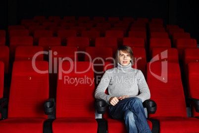 Young man sitting in the cinema alone