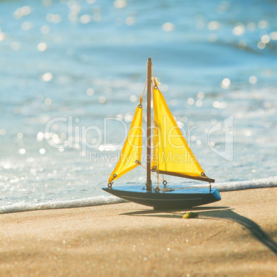 The little toy boat stands on sandy beach