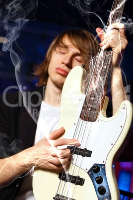 Young guitar player performing in night club