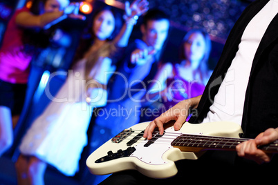 Young guitar player performing in night club