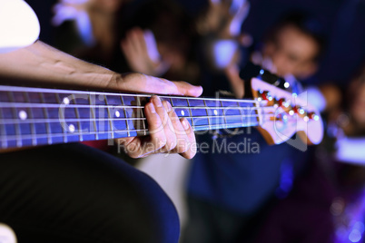 Young guitar player performing in night club