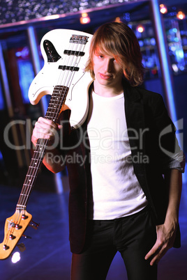 Young guitar player performing in night club