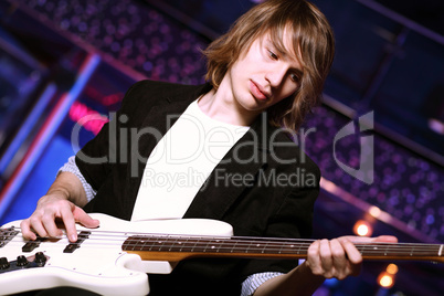 Young guitar player performing in night club