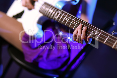 Young guitar player performing in night club