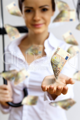 Business woman under money rain with umbrella