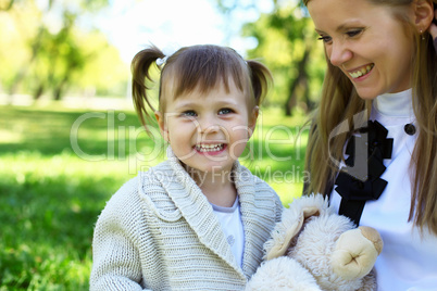 Little girl playing with mother in summer park