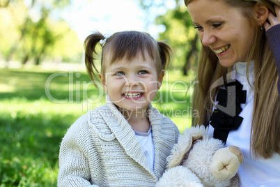 Little girl playing with mother in summer park