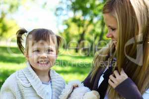 Little girl playing with mother in summer park