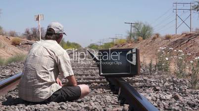 Man Sitting on the Railway Tracks With an Old, Retro TV