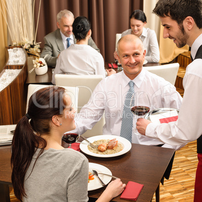 Business lunch waiter serving red wine