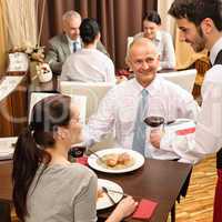 Business lunch waiter serving red wine