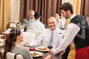 Business lunch waiter serving red wine