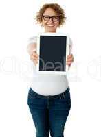 Woman showing tablet screen to camera
