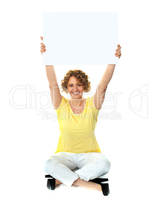 Seated woman holding blank billboard