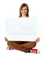 Smiling pretty teenager posing with blank placard