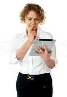 Businesswoman looking at tablet and thinking deep