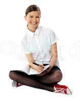 Charming girl seated on floor with notebook on her lap