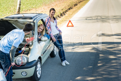 Car defect man helping two female friends