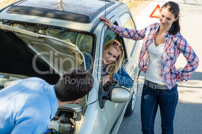 Car defect man helping two female friends