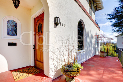 Spanish style white house with red porch and front door.