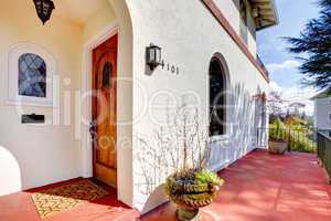 Spanish style white house with red porch and front door.