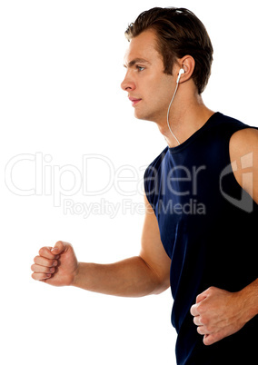 Fit athlete enjoying music in a jogging posture
