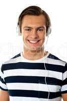 Smiling young man listening to music through headphones