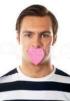 Good looking guy with heart shaped paper on his mouth
