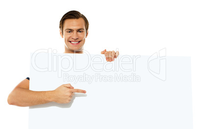 Young handsome man pointing towards blank placard