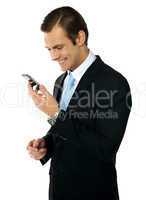 Male executive smiling as he reads message on his mobile